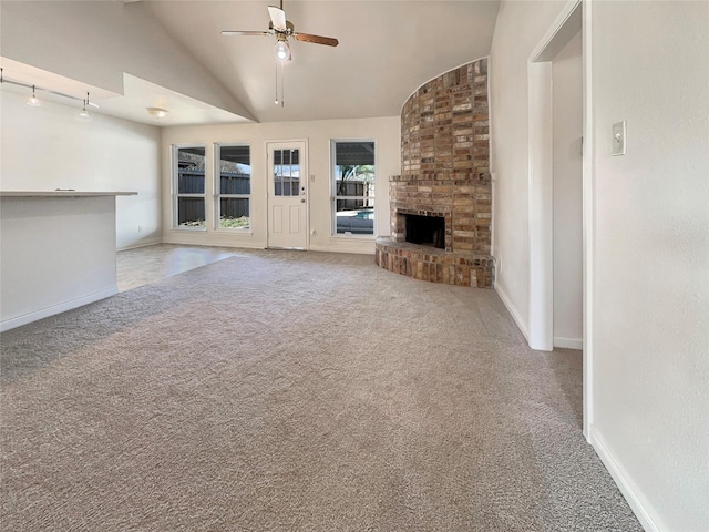 unfurnished living room featuring ceiling fan, lofted ceiling, a brick fireplace, track lighting, and light carpet