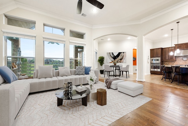 living room with ceiling fan, ornamental molding, and light hardwood / wood-style floors