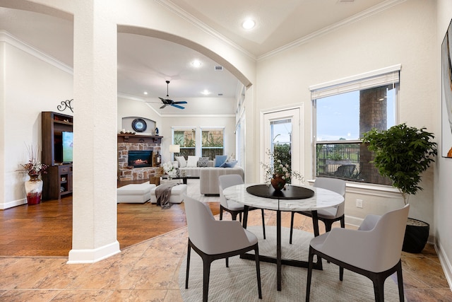 dining space with ceiling fan, a stone fireplace, and a healthy amount of sunlight