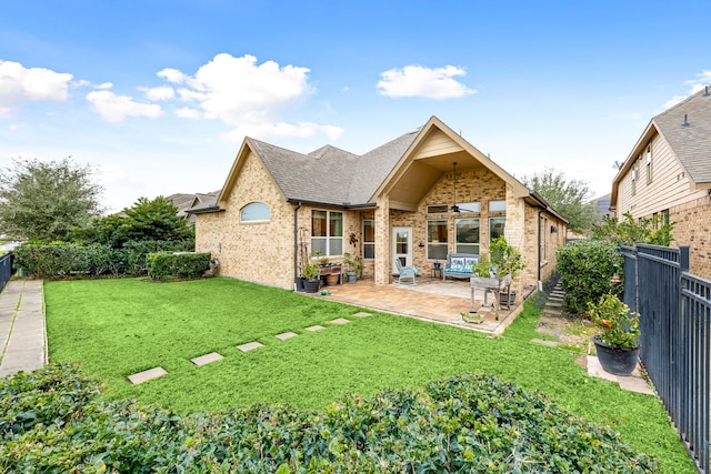 rear view of property with ceiling fan, a patio area, and a yard