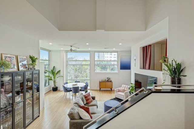 living room with light wood-type flooring, ceiling fan, and floor to ceiling windows