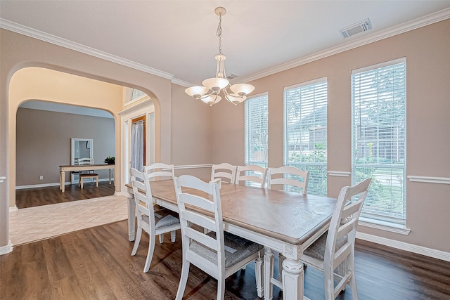 dining space with a wealth of natural light, dark hardwood / wood-style floors, ornamental molding, and a chandelier