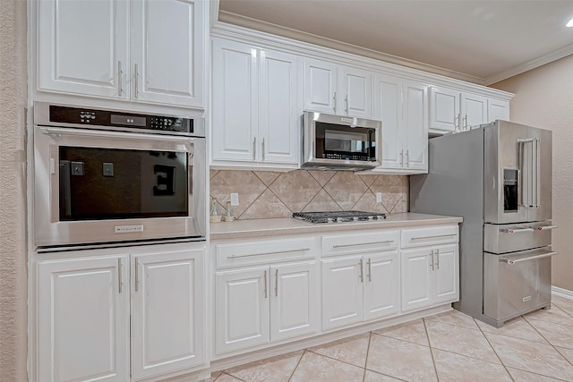 kitchen featuring light tile patterned floors, white cabinetry, appliances with stainless steel finishes, decorative backsplash, and crown molding