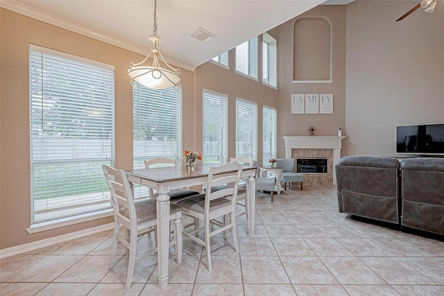 tiled dining room featuring ceiling fan, ornamental molding, and a tile fireplace