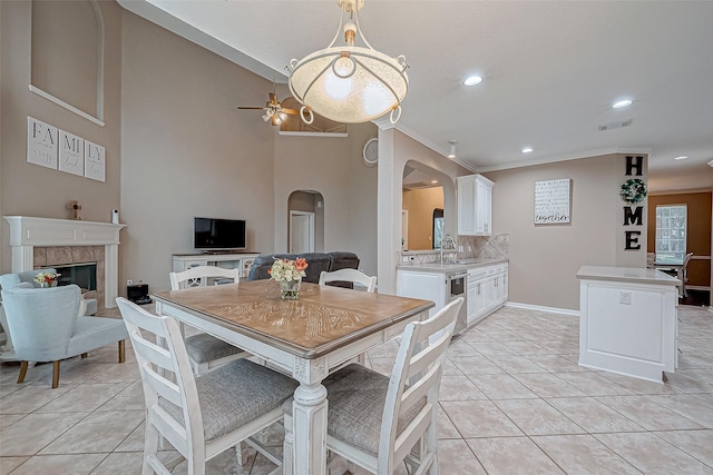 kitchen with ceiling fan, a fireplace, crown molding, white cabinetry, and light tile patterned floors