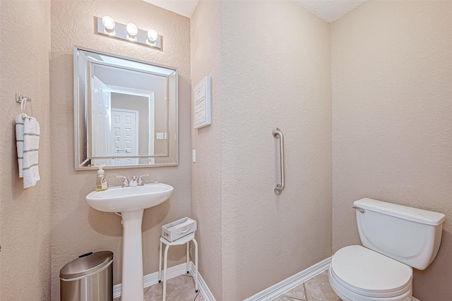 bathroom with toilet, sink, tile patterned floors, and a textured ceiling