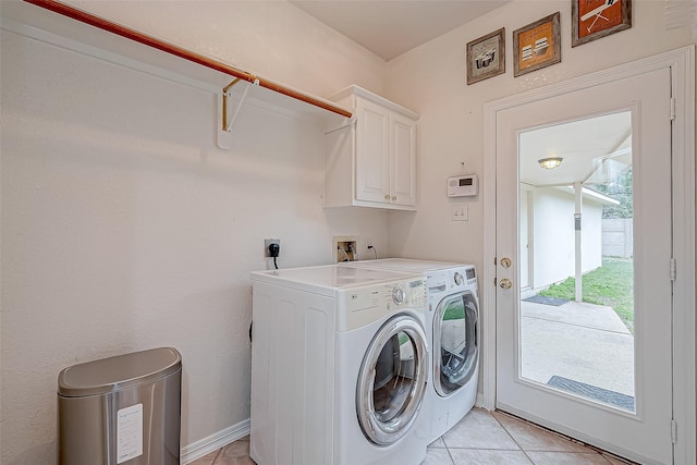 clothes washing area with light tile patterned floors, washer and dryer, and cabinets