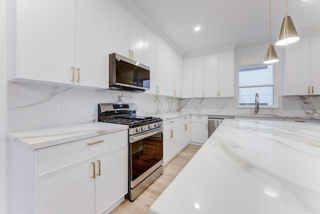 kitchen with pendant lighting, sink, white cabinets, and appliances with stainless steel finishes