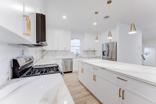 kitchen featuring white cabinetry, decorative light fixtures, appliances with stainless steel finishes, light stone countertops, and decorative backsplash