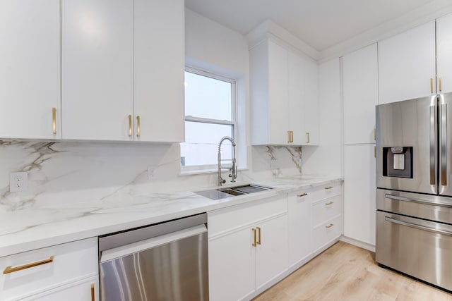 kitchen with sink, backsplash, stainless steel appliances, light stone countertops, and white cabinets