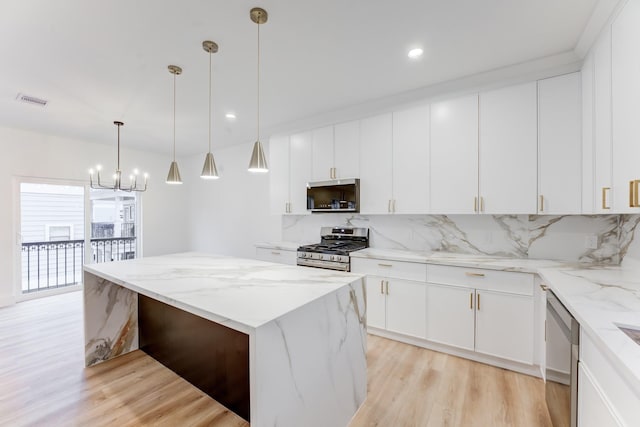 kitchen with stainless steel appliances, light stone countertops, decorative backsplash, white cabinets, and decorative light fixtures