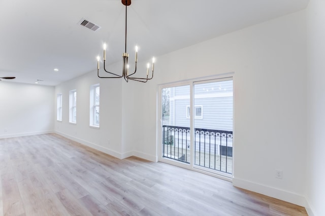 unfurnished dining area with plenty of natural light, a chandelier, and light wood-type flooring