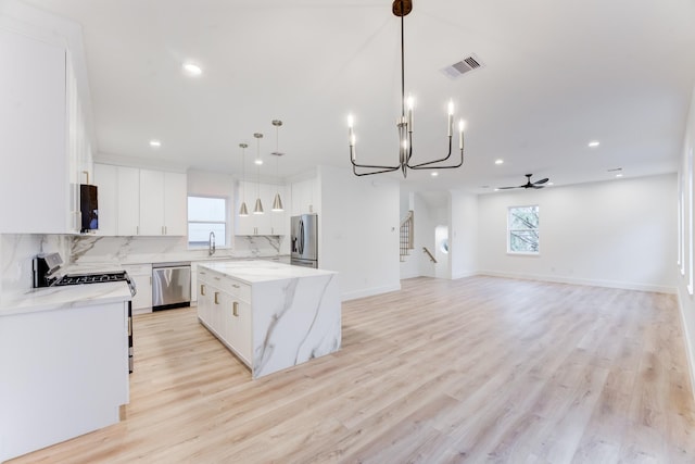 kitchen featuring white cabinetry, hanging light fixtures, stainless steel appliances, and a center island