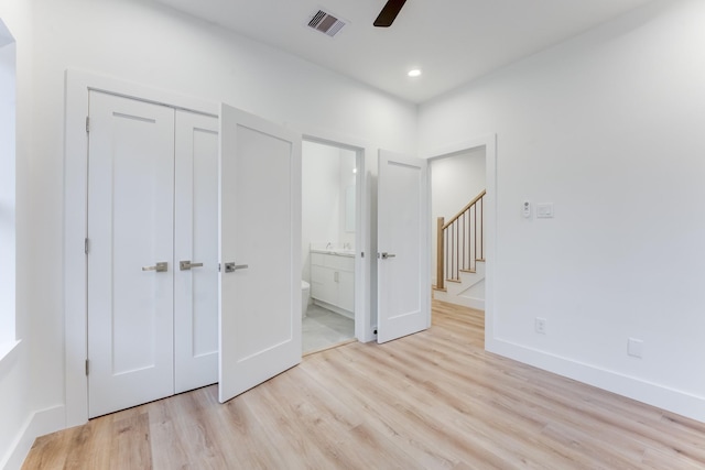 unfurnished bedroom with ensuite bath, a closet, ceiling fan, and light wood-type flooring