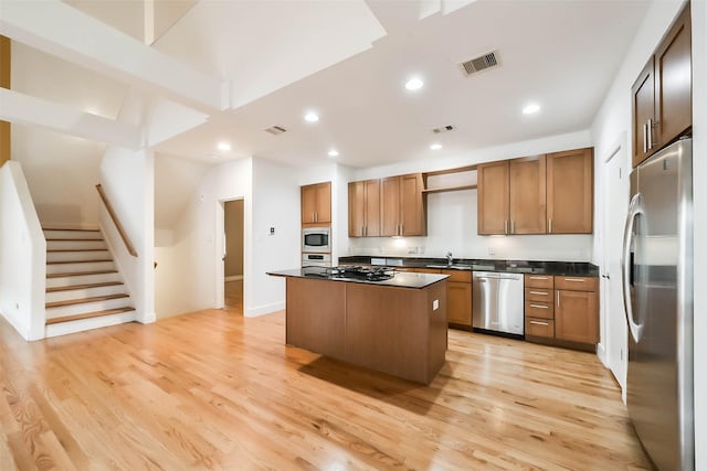 kitchen with light wood-type flooring, sink, stainless steel appliances, and a kitchen island