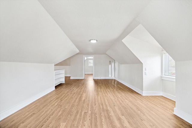 additional living space featuring lofted ceiling, a wealth of natural light, and light wood-type flooring