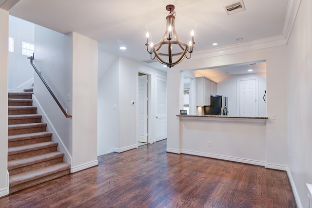 unfurnished living room featuring dark hardwood / wood-style flooring, ornamental molding, and a chandelier