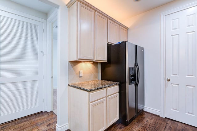 kitchen featuring dark wood-type flooring, dark stone counters, stainless steel fridge, and light brown cabinets