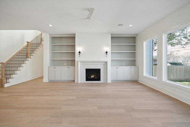 unfurnished living room featuring built in features, light hardwood / wood-style flooring, and ceiling fan