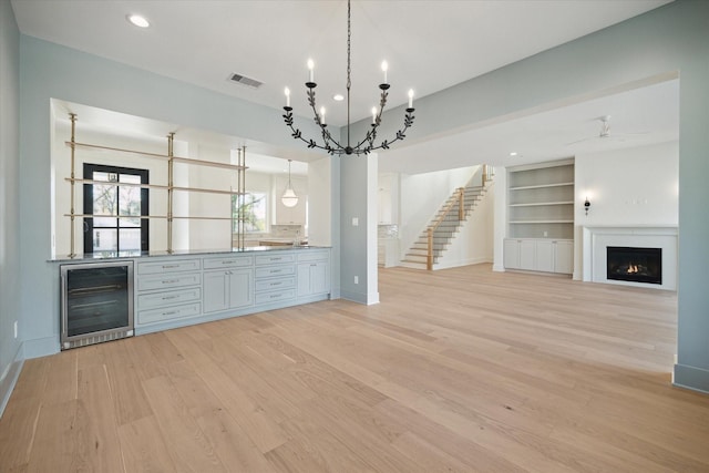 bar with tasteful backsplash, beverage cooler, pendant lighting, and light hardwood / wood-style floors