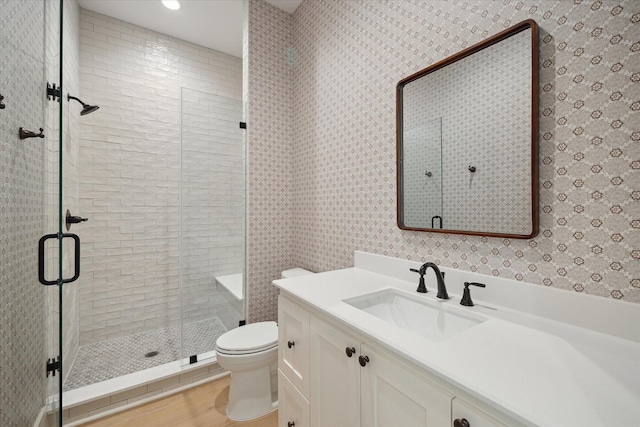 bathroom with toilet, wood-type flooring, an enclosed shower, and vanity