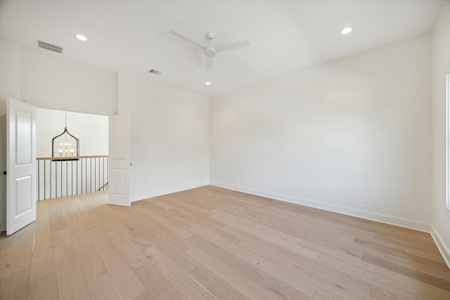 unfurnished room featuring ceiling fan with notable chandelier and light hardwood / wood-style flooring