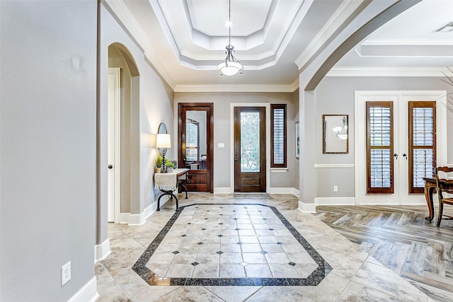 entrance foyer featuring a tray ceiling, ornamental molding, and french doors