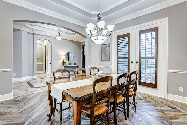 dining room with a raised ceiling, an inviting chandelier, light parquet floors, and ornamental molding