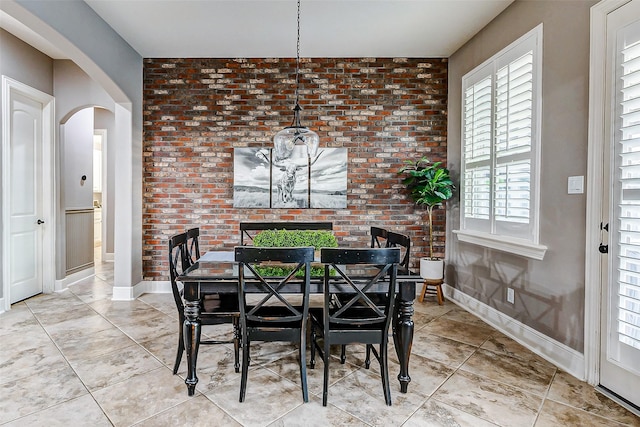 dining space featuring plenty of natural light and brick wall