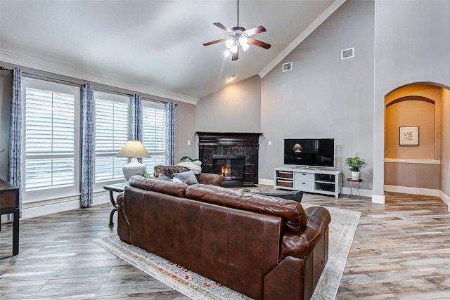 living room with light wood-type flooring, ceiling fan, crown molding, and high vaulted ceiling