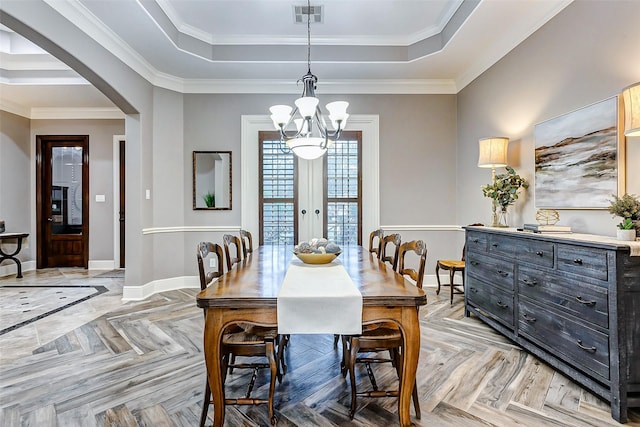 dining room with light parquet floors, ornamental molding, and a raised ceiling