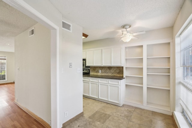 kitchen featuring ceiling fan, backsplash, white cabinetry, and a textured ceiling