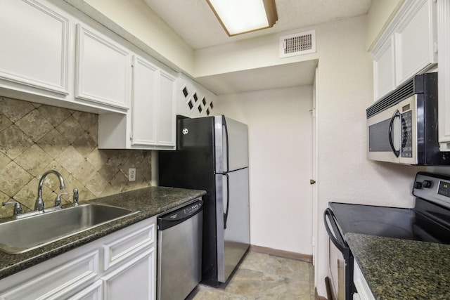 kitchen with white cabinetry, appliances with stainless steel finishes, tasteful backsplash, dark stone counters, and sink