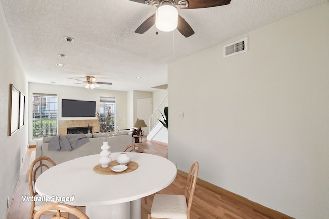 dining room with ceiling fan, light wood-type flooring, and a textured ceiling