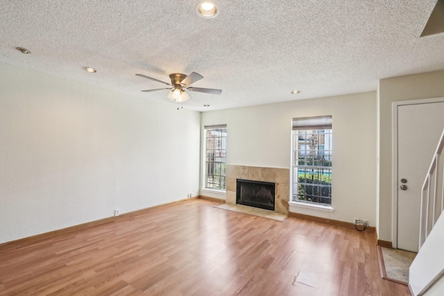 unfurnished living room featuring a textured ceiling, ceiling fan, light hardwood / wood-style floors, and a fireplace