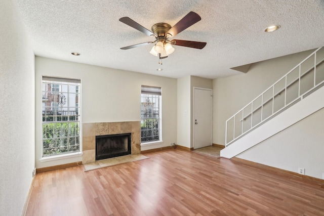 unfurnished living room featuring a textured ceiling, ceiling fan, a fireplace, and hardwood / wood-style flooring