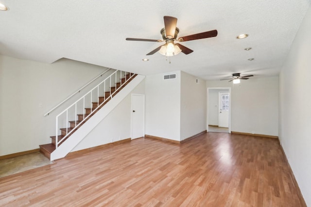 unfurnished living room featuring ceiling fan, hardwood / wood-style floors, and a textured ceiling