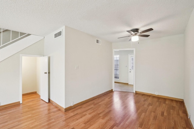 empty room with a textured ceiling, ceiling fan, and hardwood / wood-style floors