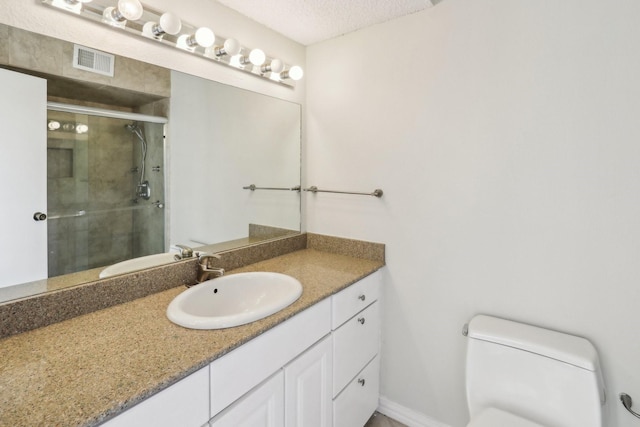 bathroom with walk in shower, vanity, toilet, and a textured ceiling