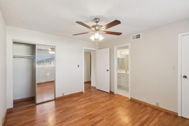 unfurnished bedroom featuring ceiling fan, hardwood / wood-style floors, a closet, and ensuite bath