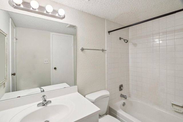 full bathroom with toilet, tiled shower / bath, vanity, and a textured ceiling