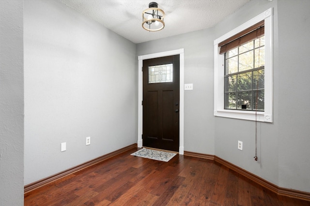 entrance foyer with dark wood-type flooring and a textured ceiling