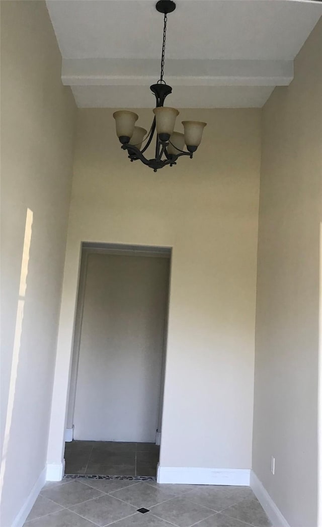 empty room featuring beamed ceiling and an inviting chandelier