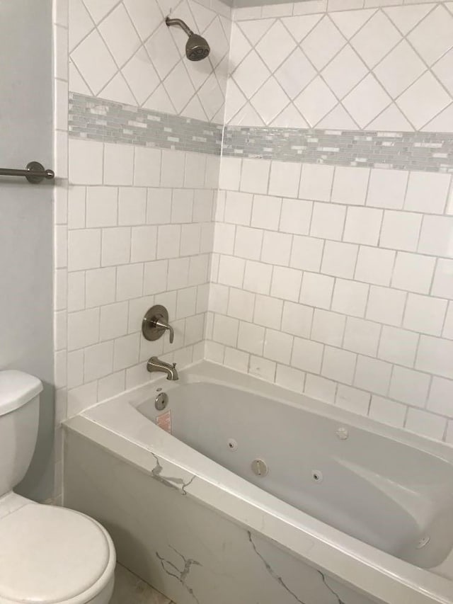 bathroom with toilet and tiled shower / bath