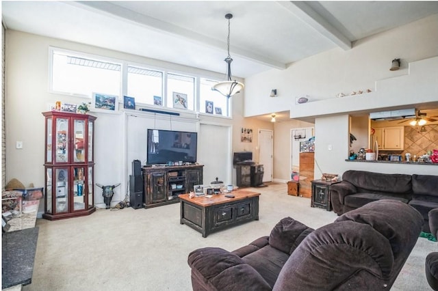 carpeted living room with ceiling fan, beam ceiling, and a high ceiling