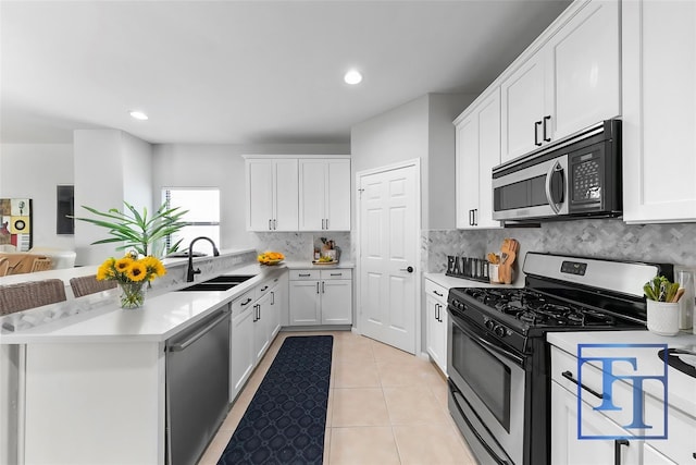 kitchen with appliances with stainless steel finishes, white cabinetry, decorative backsplash, sink, and light tile patterned flooring