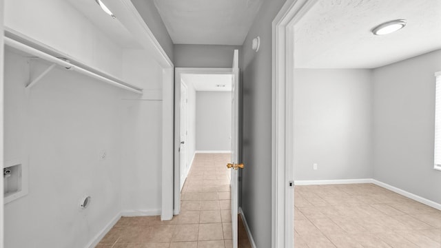 corridor featuring a textured ceiling and light tile patterned floors