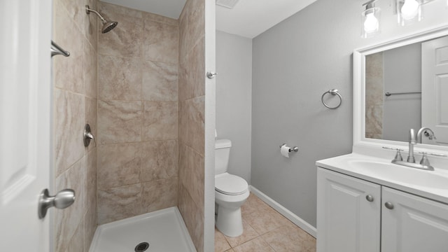 bathroom featuring toilet, tile patterned floors, tiled shower, and vanity