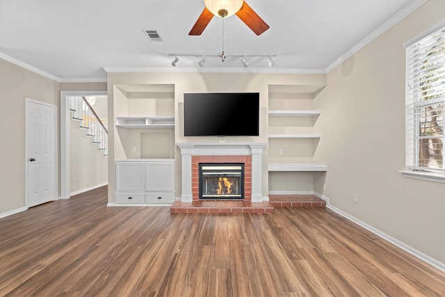 unfurnished living room with crown molding, built in features, ceiling fan, hardwood / wood-style floors, and a fireplace