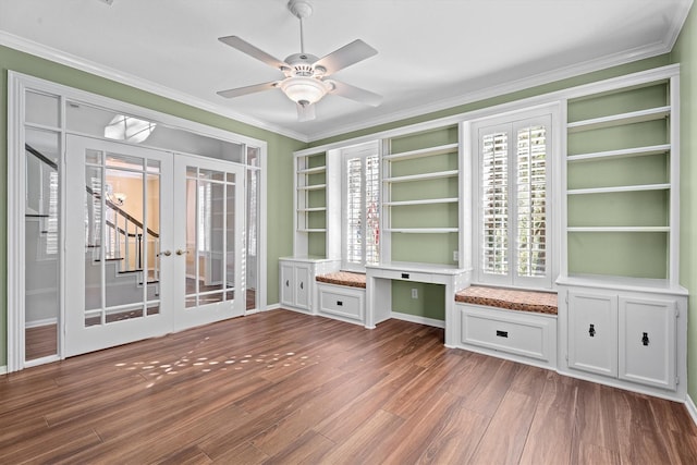 unfurnished living room featuring hardwood / wood-style flooring, ceiling fan, built in desk, ornamental molding, and french doors